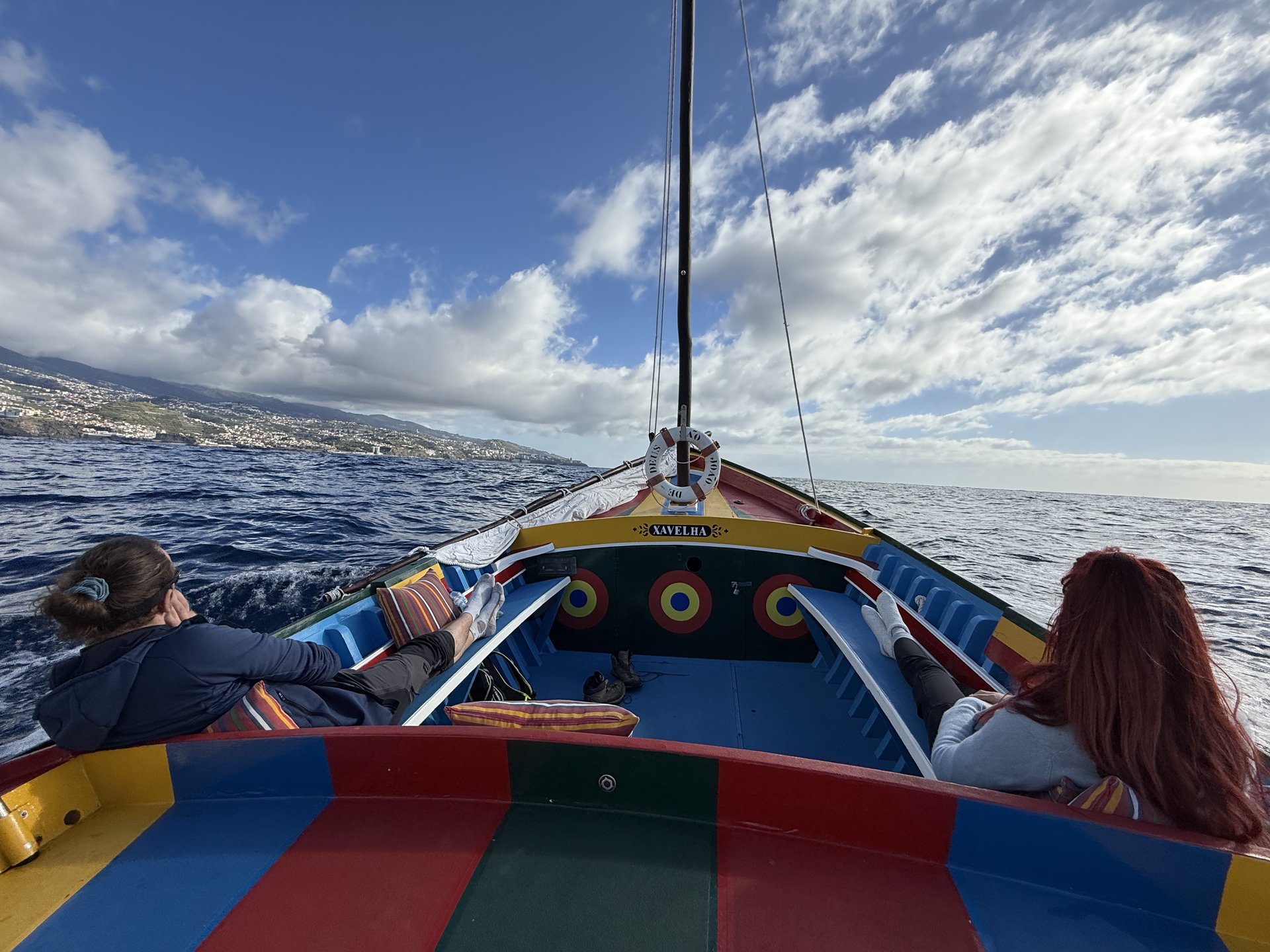 Guests seated on the deck as the boat follows the coastline